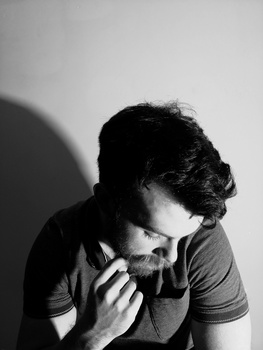 A monochrome portrait of a young man against a white wall